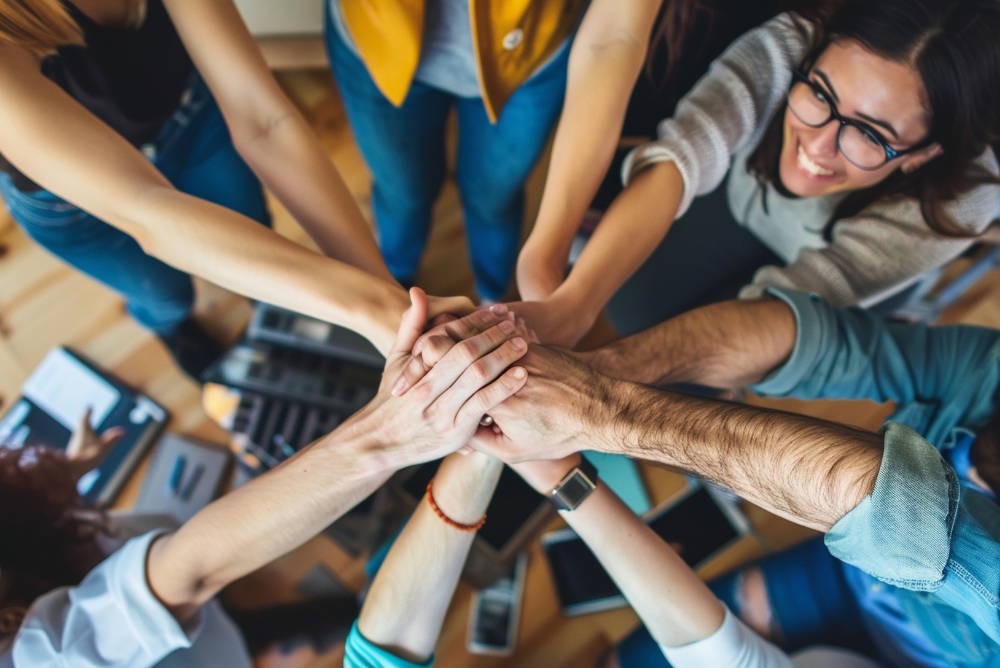 Team of coworkers joining hands to show unity and engagement.