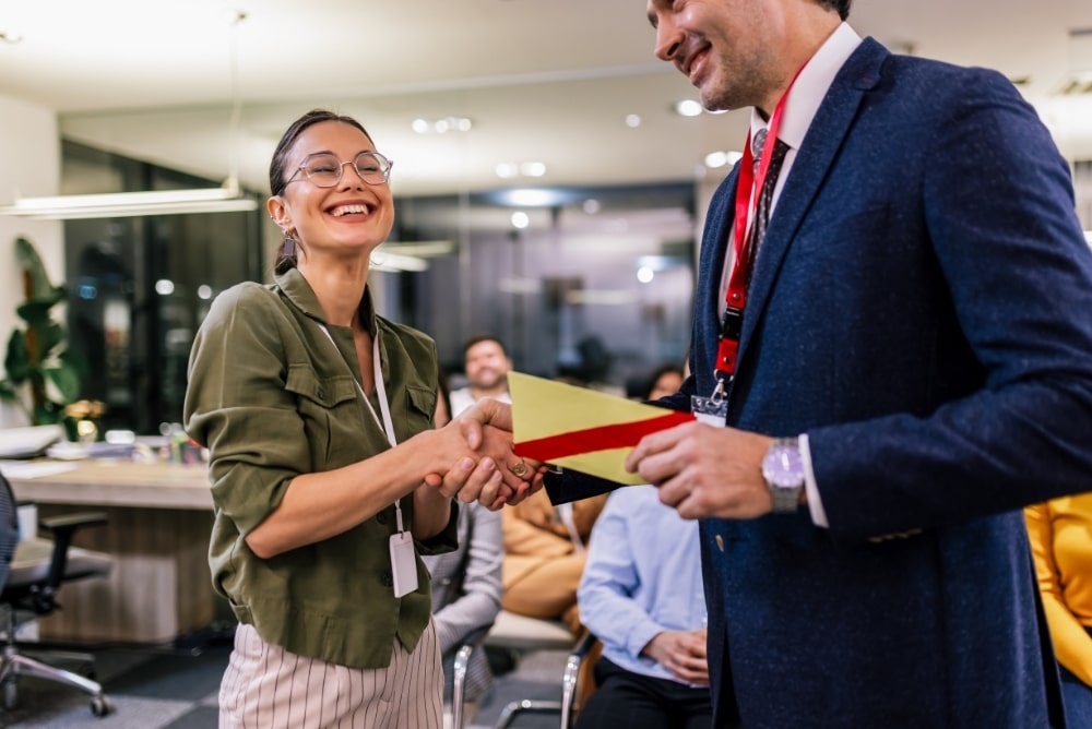Employee receiving recognition from a manager during a workplace awards moment.