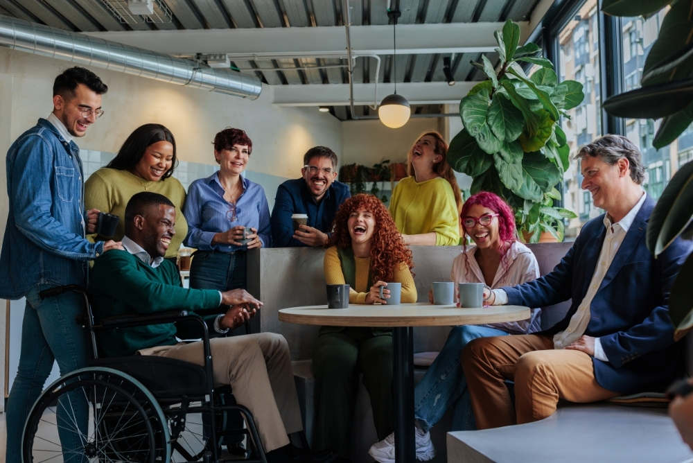 Diverse employees laughing and connecting during a casual team gathering, reflecting a strong culture committee that supports recognition and engagement.