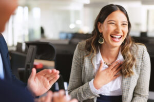 Smiling professional receiving workplace recognition from a colleague, highlighting employee appreciation, engagement, and positive company culture.
