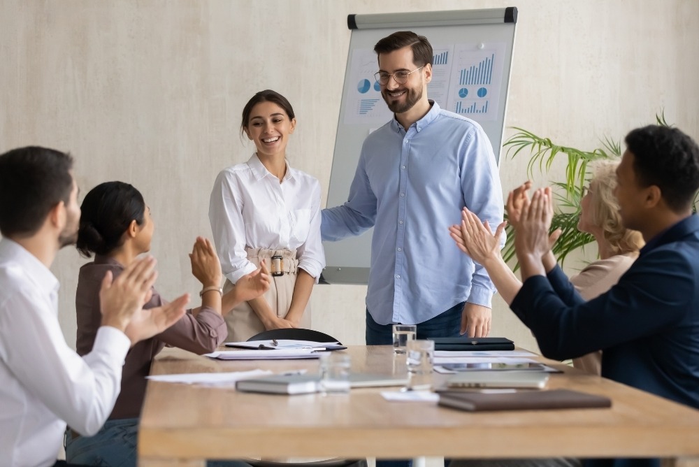 Team celebrating employee recognition during a workplace meeting