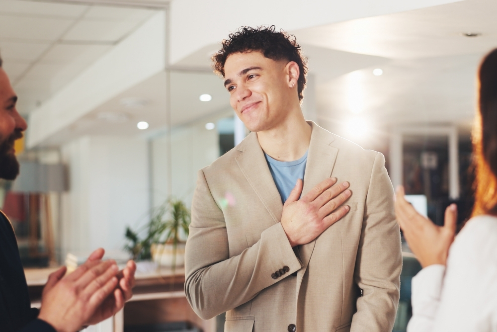 Employee being applauded by colleagues while expressing gratitude during a workplace recognition moment, representing Q2 recognition campaigns and celebrating achievements in spring.