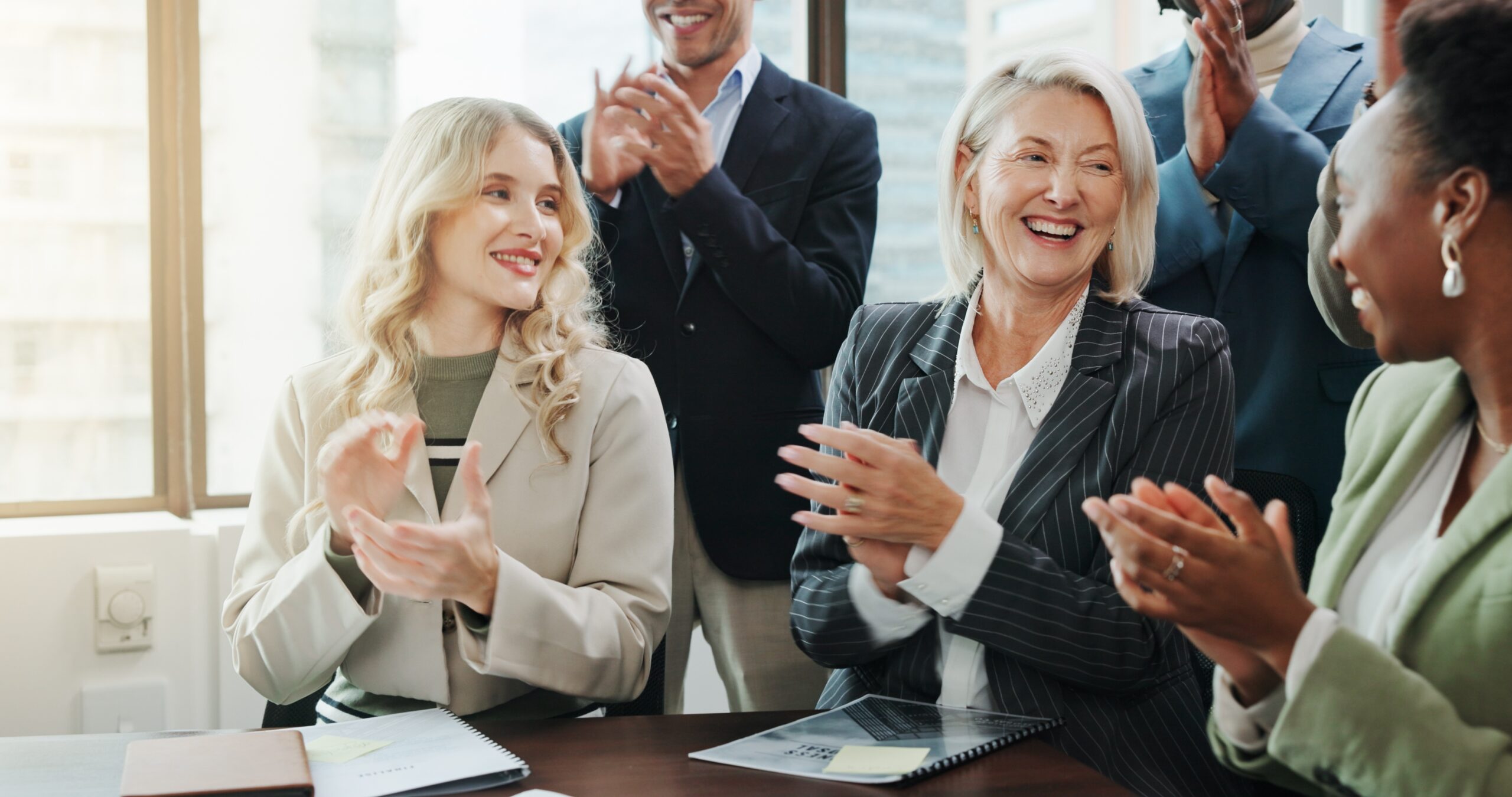 Employees applauding a colleague during a workplace recognition moment.