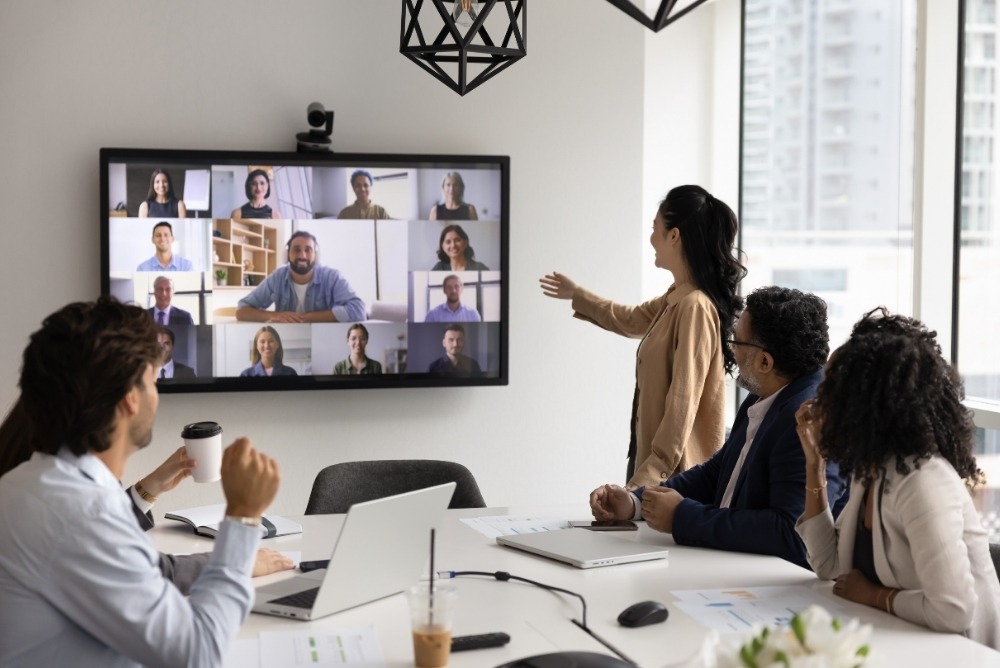 Team collaborating in a hybrid meeting, connecting in-office and remote employees