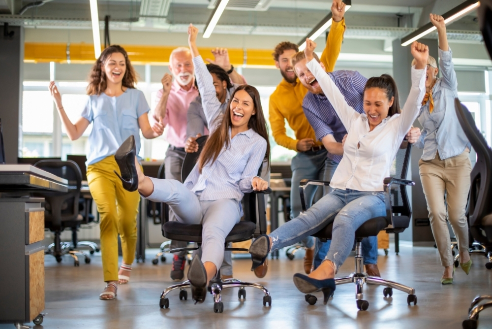 Team of employees celebrating together in office, showing engagement and participation driven by workplace gamification