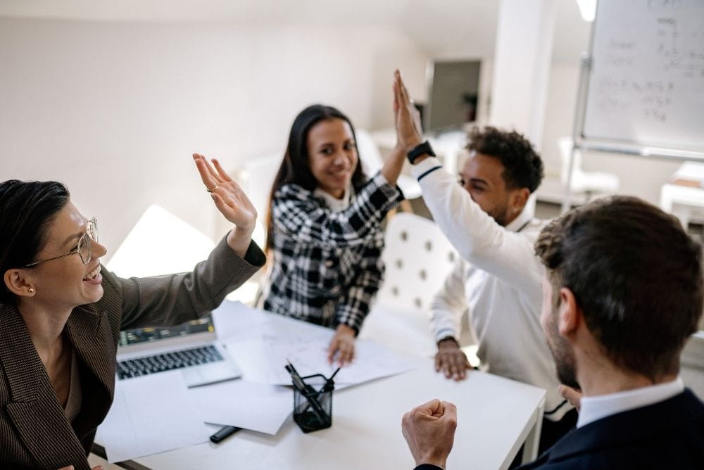 Sales team celebrating a shared win with high fives at work