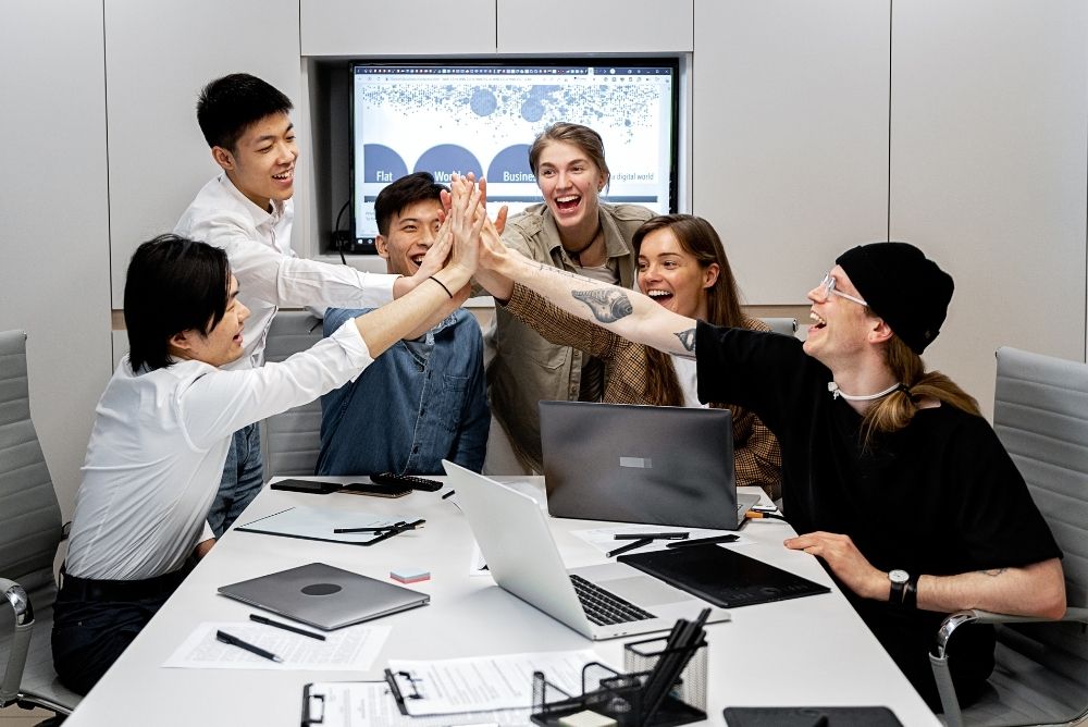 Sales team celebrating together with high fives during a meeting