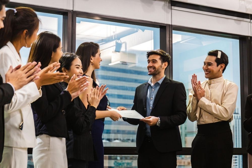 Employees applauding a colleague receiving recognition at work